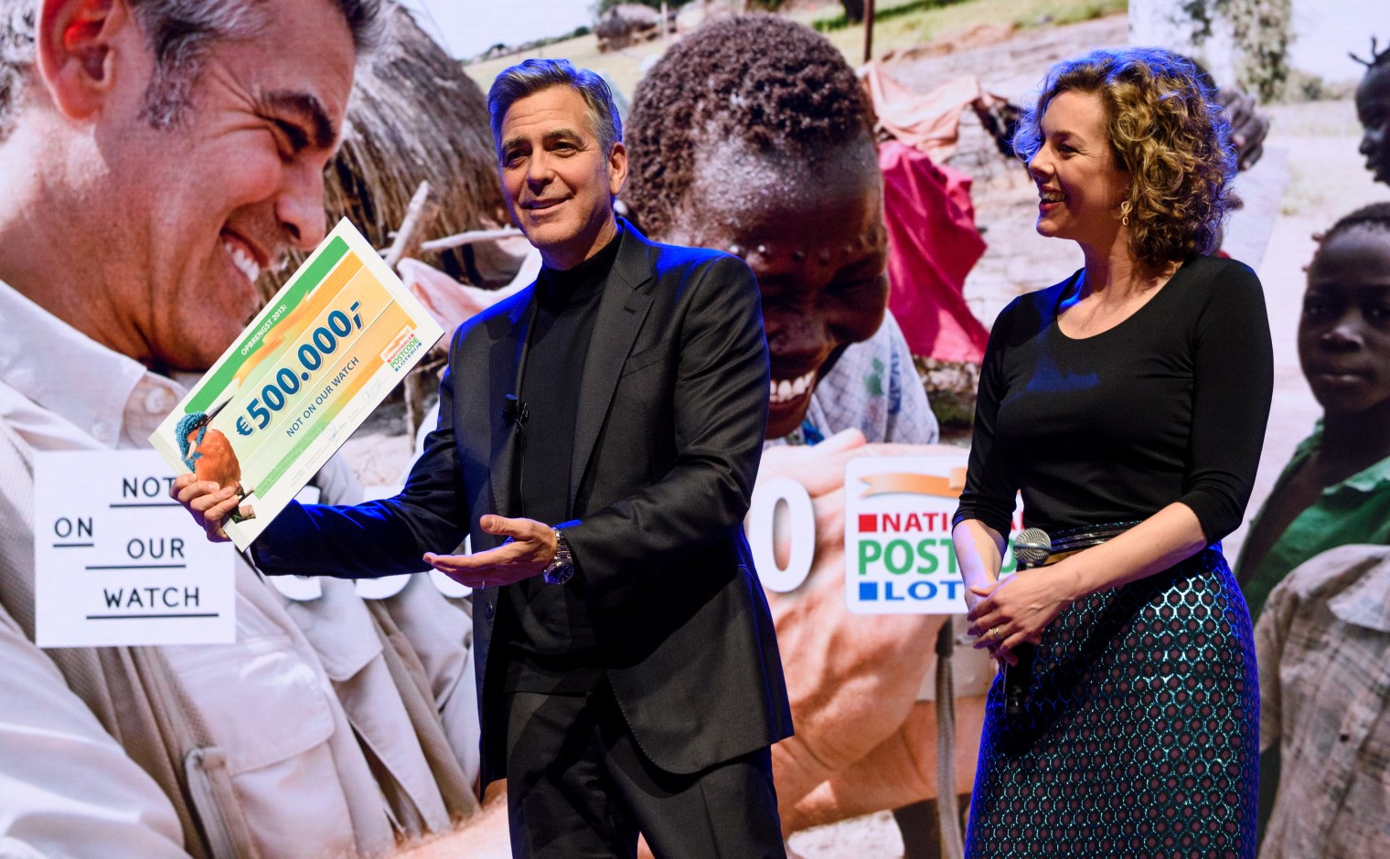 Mensenrechtenactivist en acteur George Clooney neemt een cheque van 500.000 euro in ontvangst voor zijn organisatie Not On Our Watch.