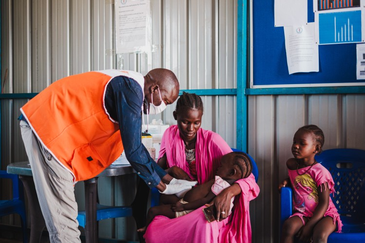 Een kind krijgt hulp van een World Vision-medewerker (C) World Vision