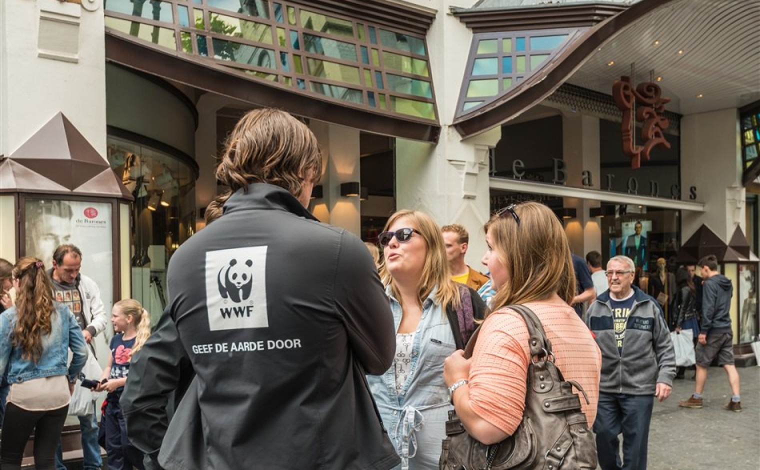 Jonge man in gesprek met twee vrouwen om donateurs leden te werven voor het Wereld Natuur Fonds.